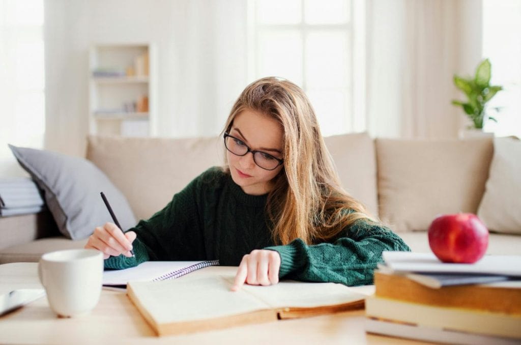 girl sitting at coffee table with book and notebook