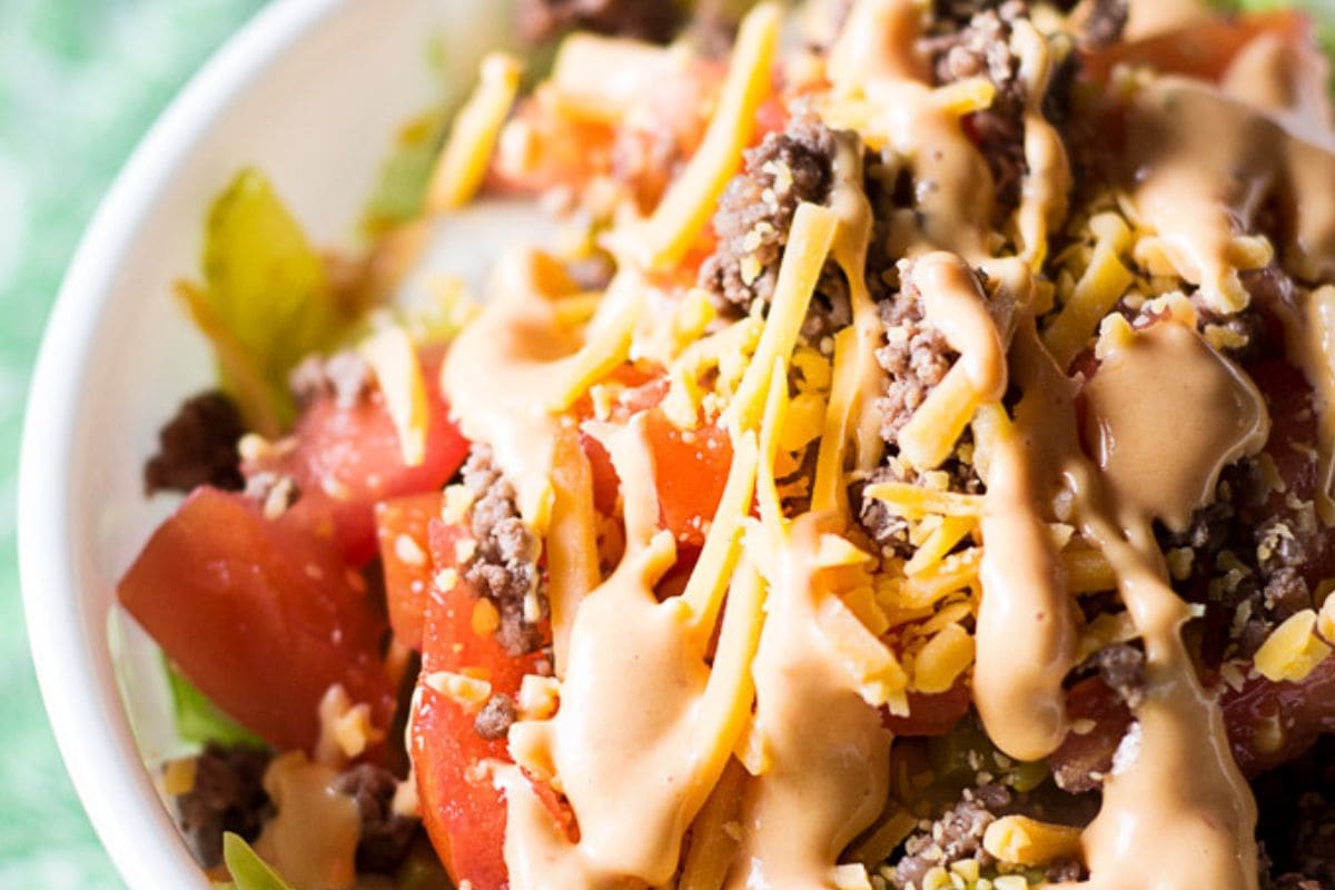 cheeseburger salad topped with Mac sauce in a white bowl