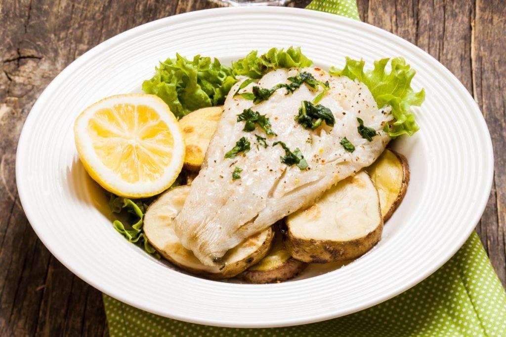 cod and potatoes with lemon on white plate
