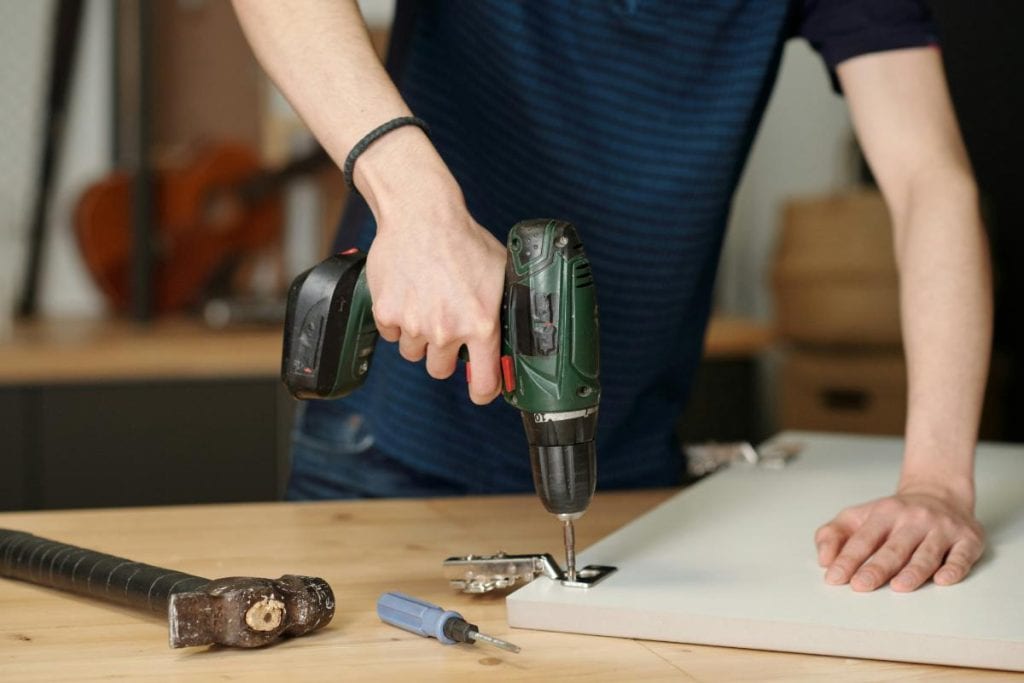 man's hands using a drill to attach hardware