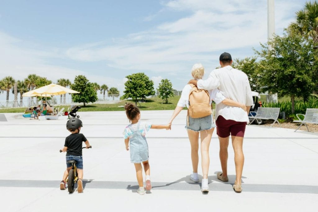 family of 4 walking on a sunny day with little boy riding bike