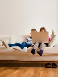 boy and girl using laptop on sofa