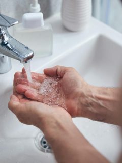 person washing hands at bathroom sink