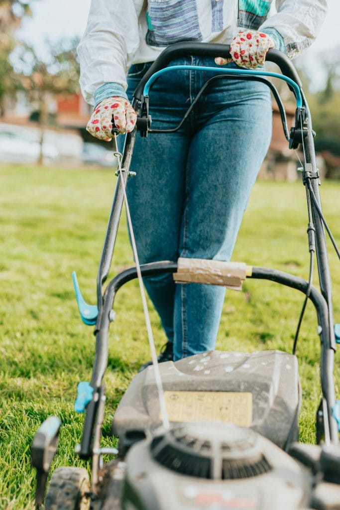 woman pulling string on lawn mower