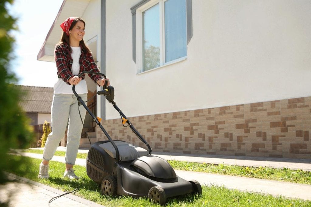 a woman cutting the grass with a lawn mower