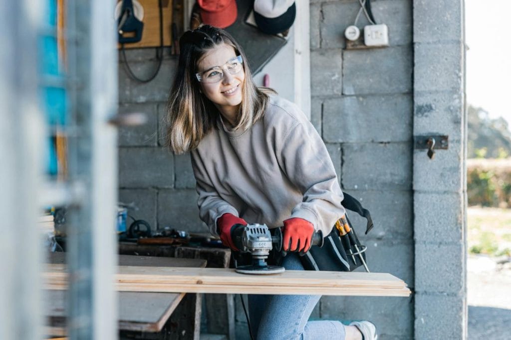 woman using a sander in a garage