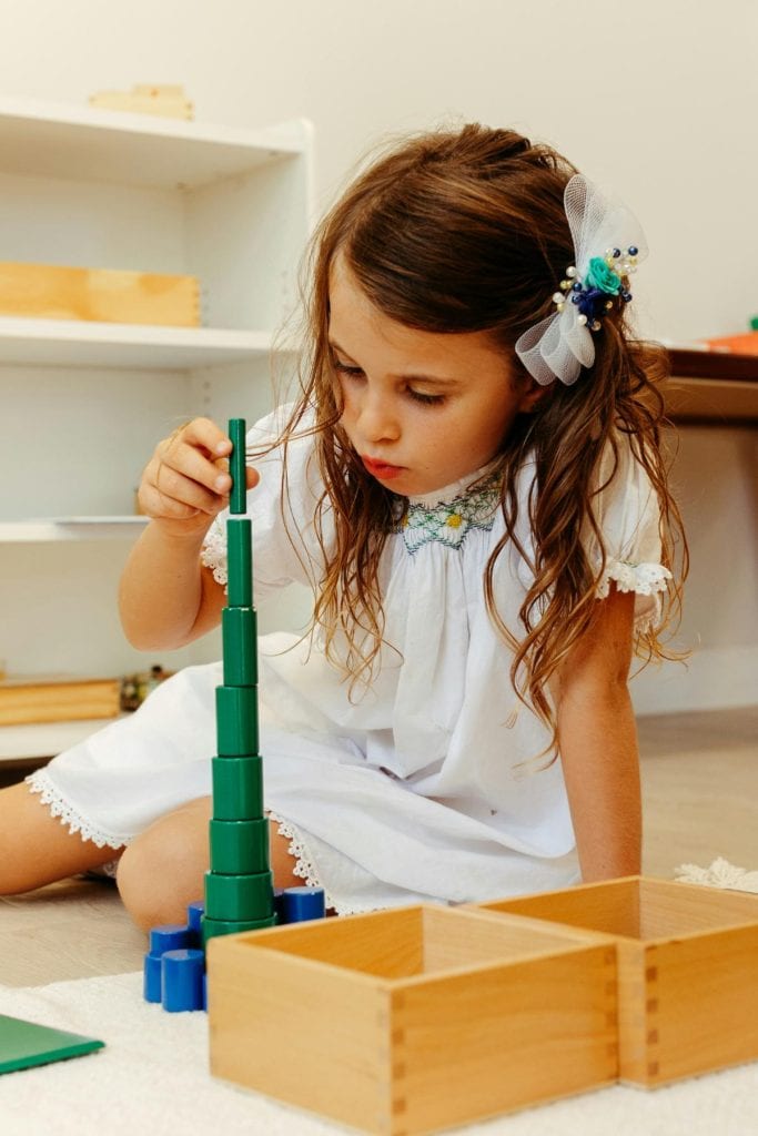 little girl in dress stacking wooden blocks