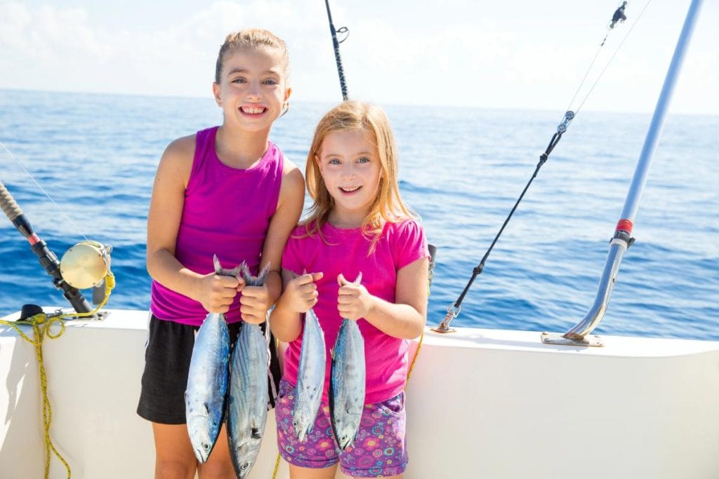 girls on a boat holding fish they caught