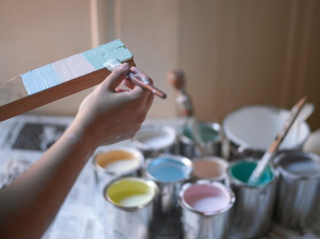 person trying several paint colors on a board