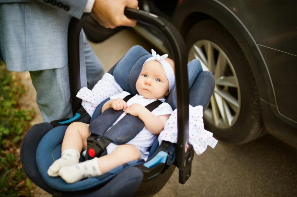 dad putting baby in carseat in the car