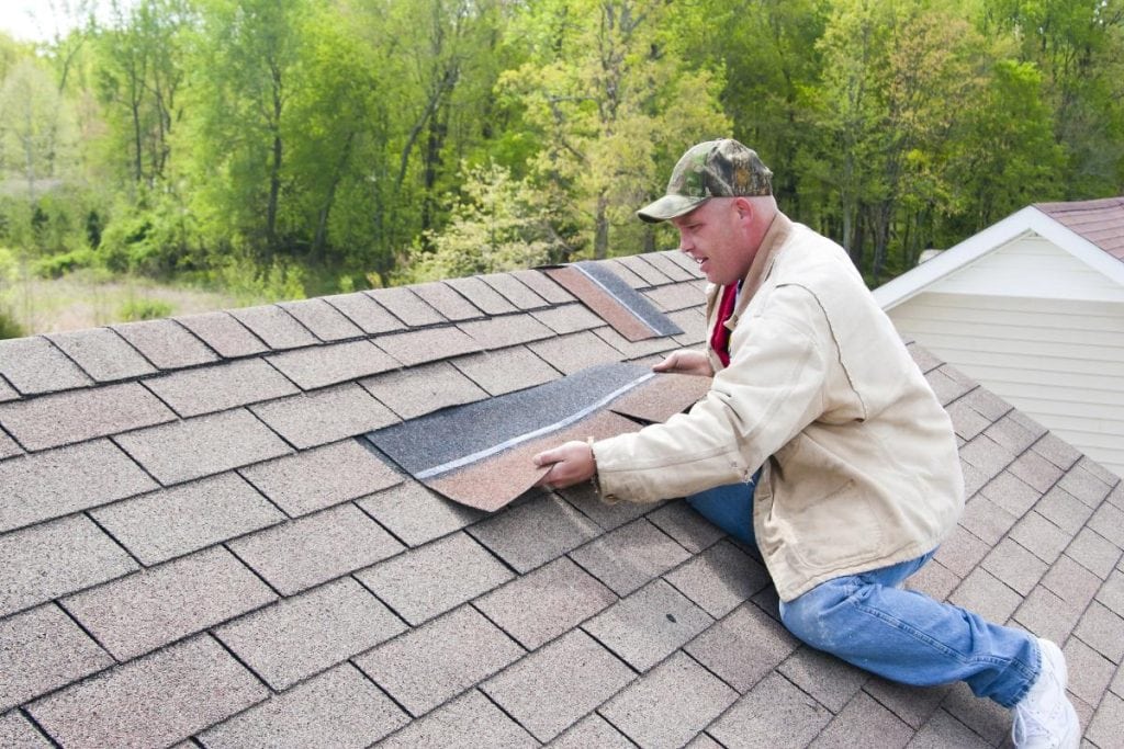 man repairing a roof after a storm