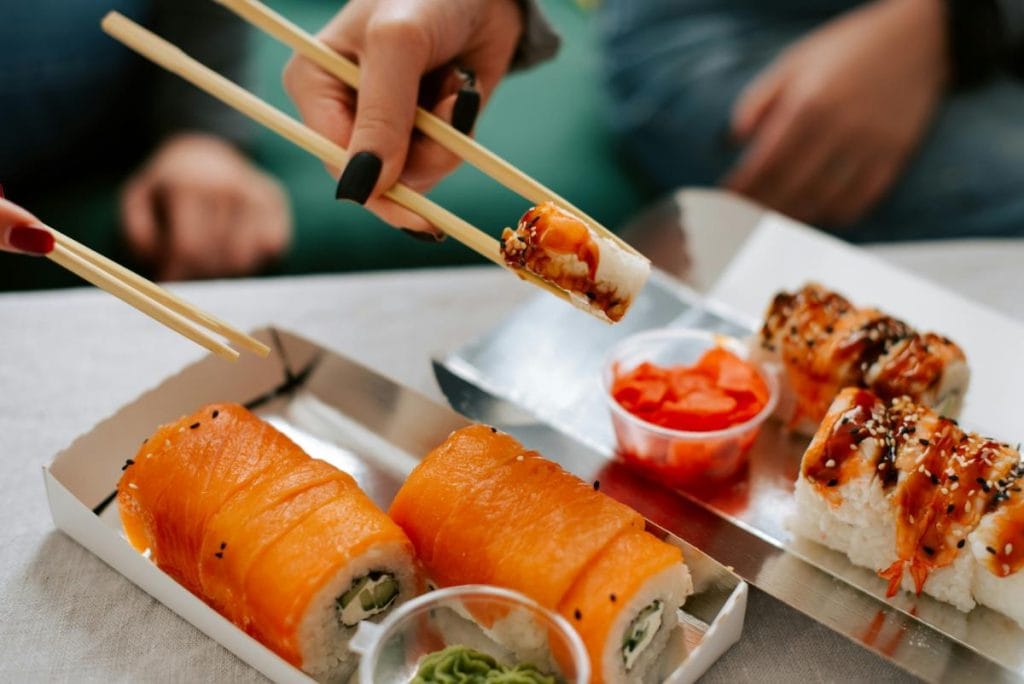 two people eating sushi with chopsticks