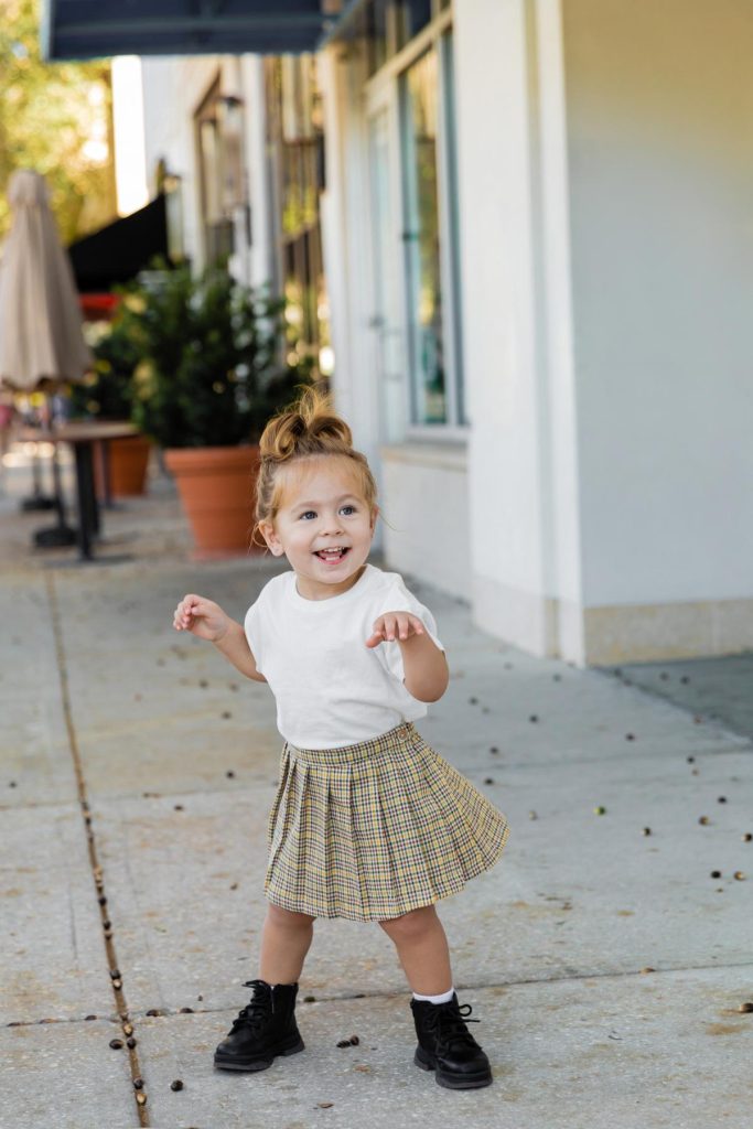 toddler girl wearing black boots on a sidewalk