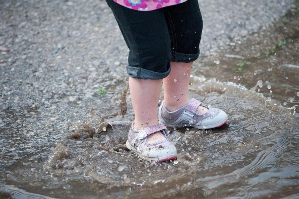 toddler jumping in puddle with shoes on