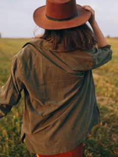 woman in hat walking through a field