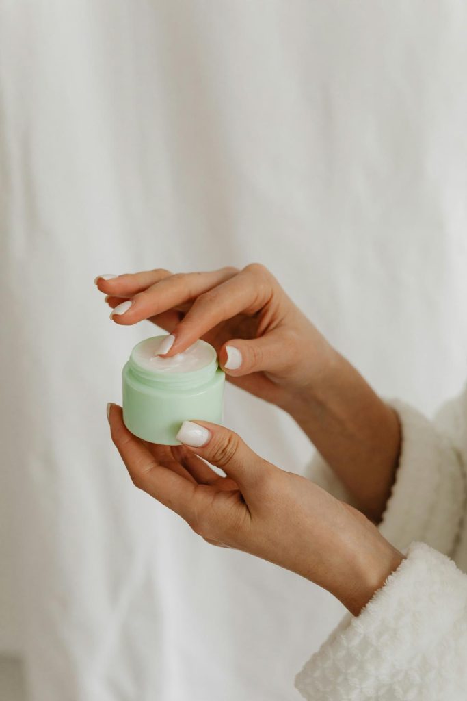 woman's hands holding jar of moisturizing cream