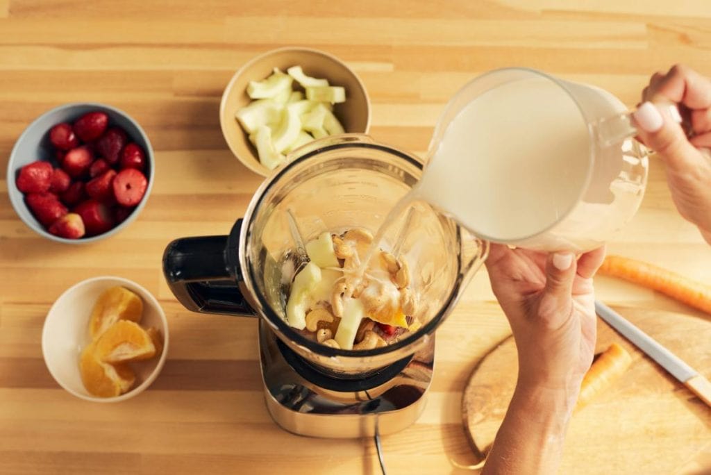 adding smoothie ingredients to a blender