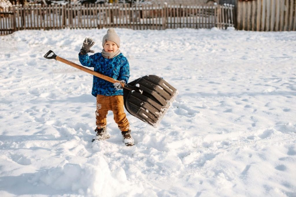 little boy with large snow shovel