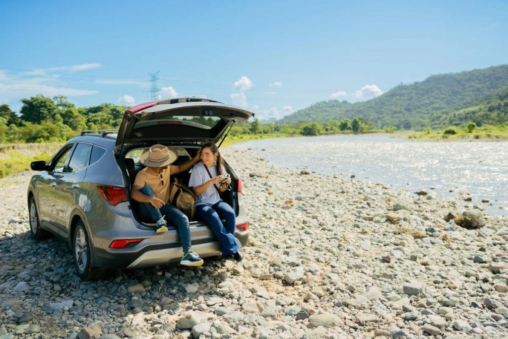 couple sitting in back of suv with hatch open