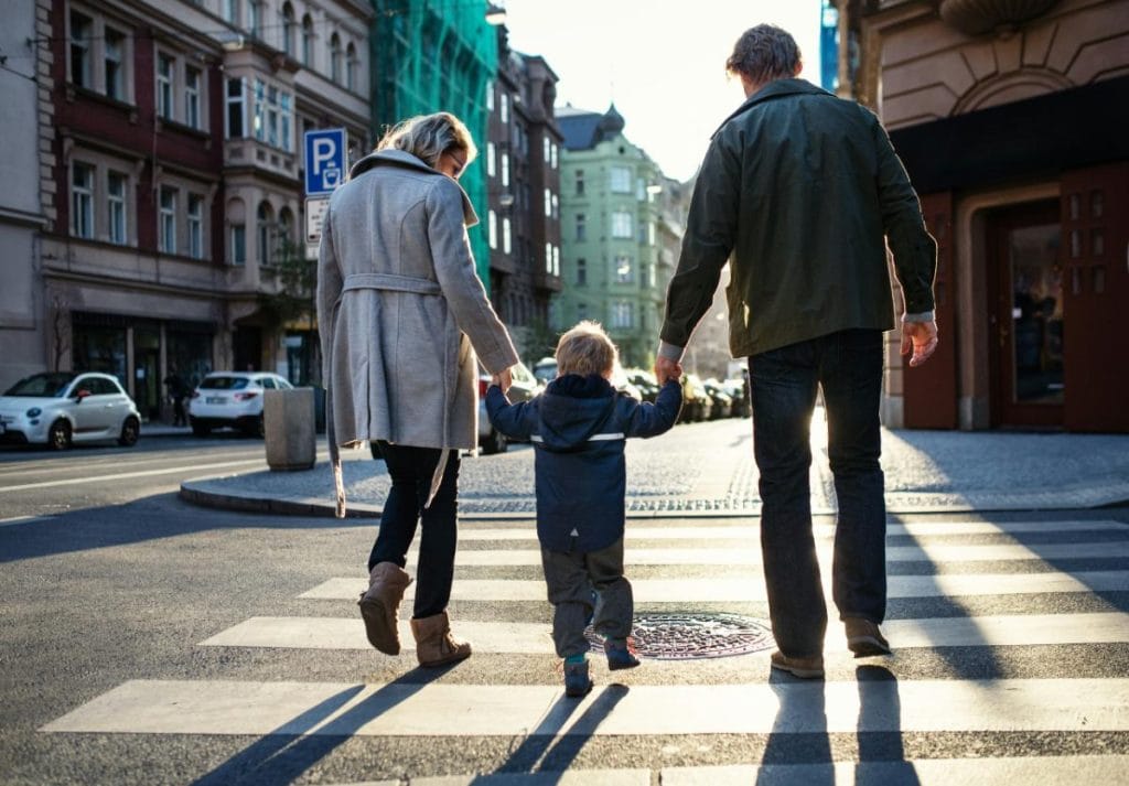 family of three walking through crosswalk