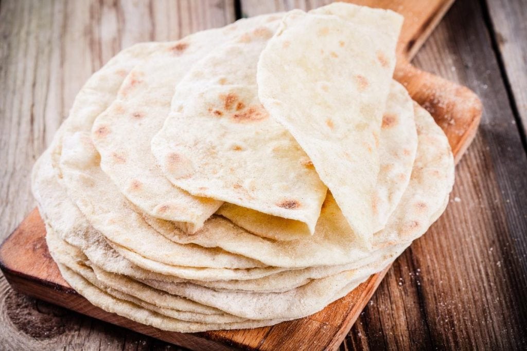 stack of homemade tortillas on cutting board