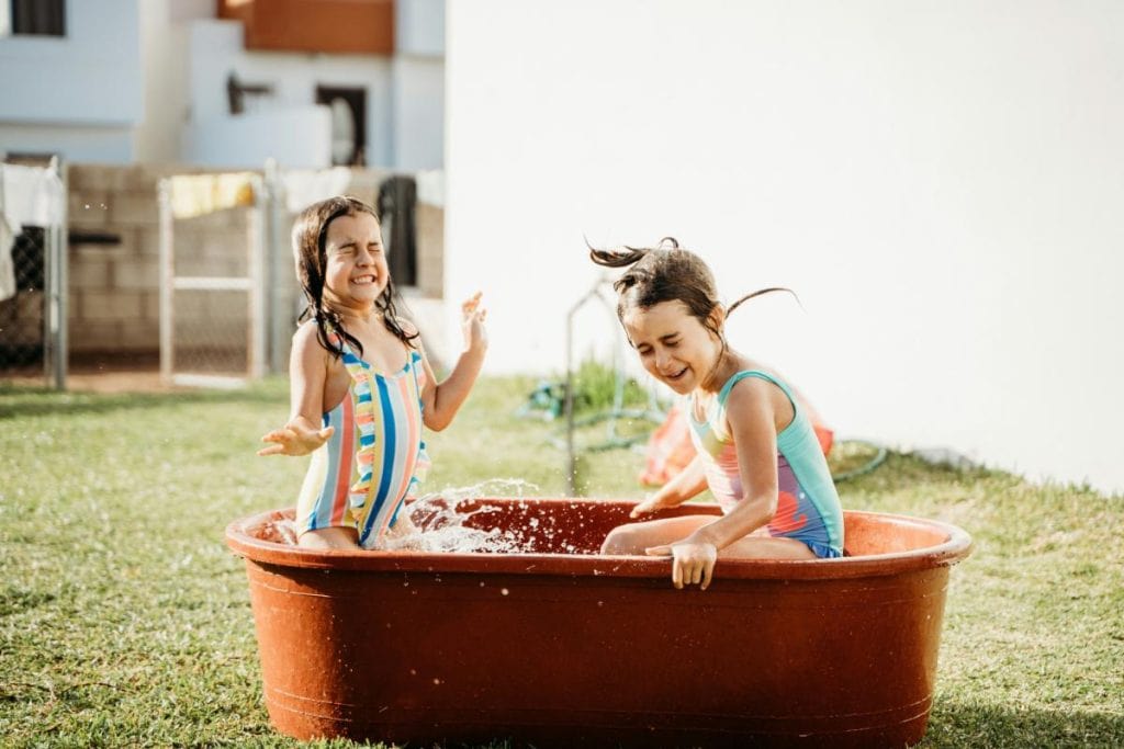 girls playing in a large tub of water outdoors