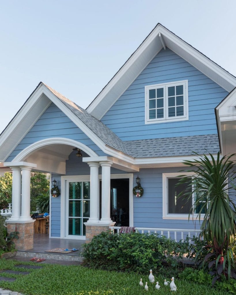 a light blue house with white columns and lovely landscaping