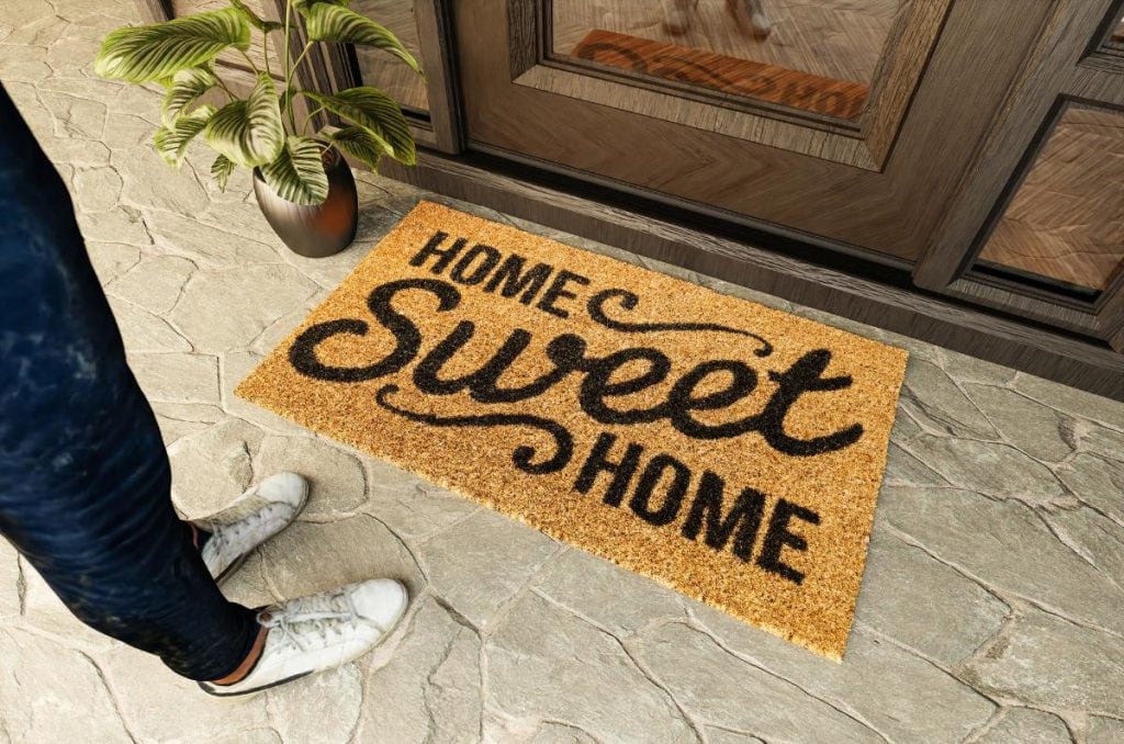 person standing in front of welcome mat that says home sweet home