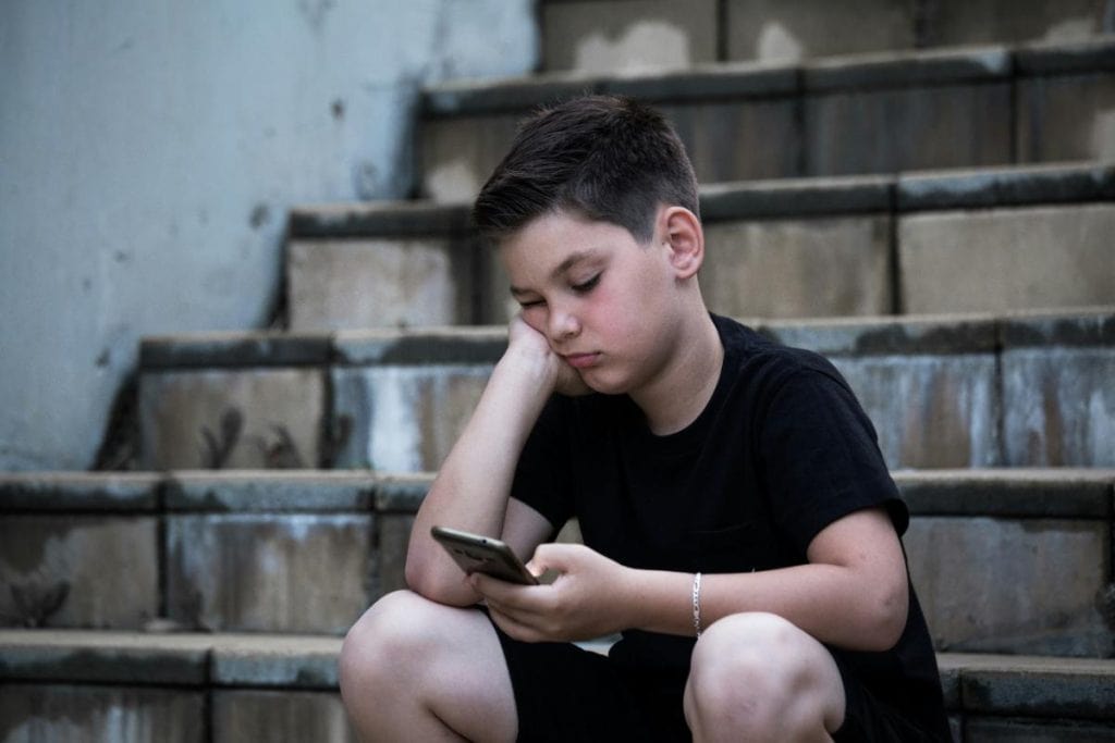 teen boy looking sadly at phone