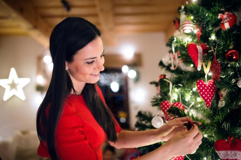 woman adding ornaments to tree