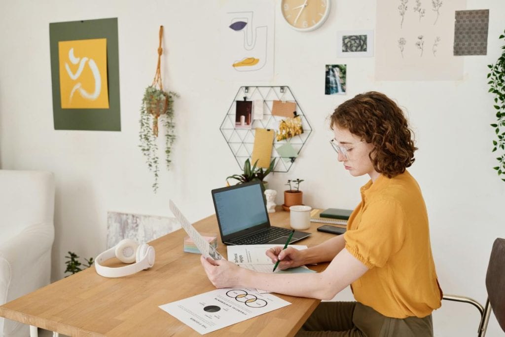 woman in mustard yellow shirt sitting at desk in home office