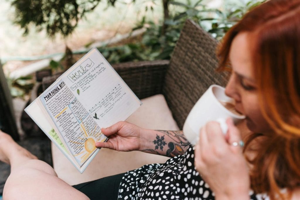 woman drinking tea and looking at bullet journal