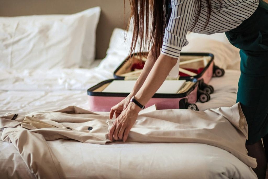 woman packing a suitcase and getting ready to add a long jacket