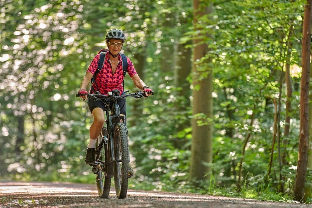 woman riding a bike through forested area