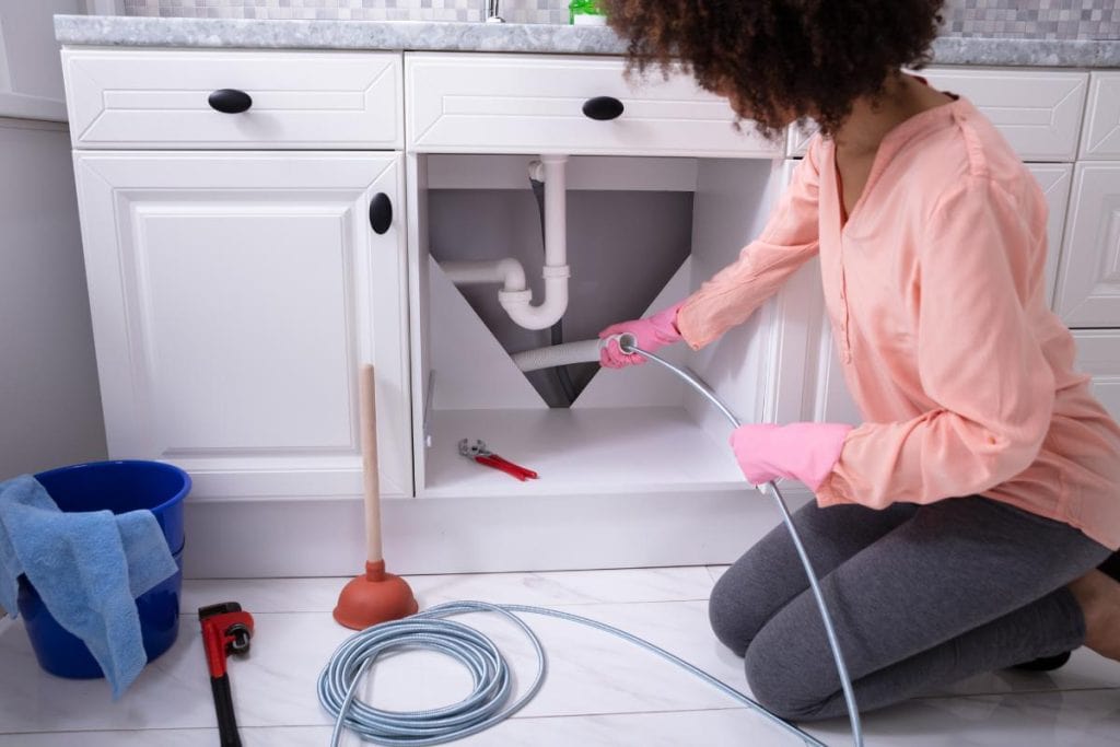 woman snaking drain