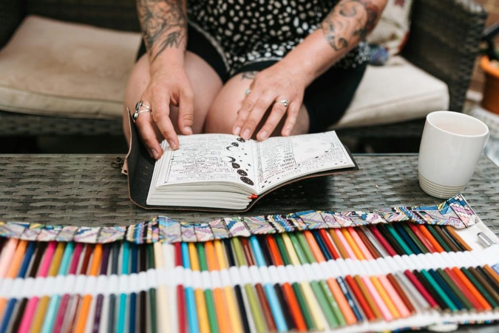 woman with a journal and lots of colored pencils