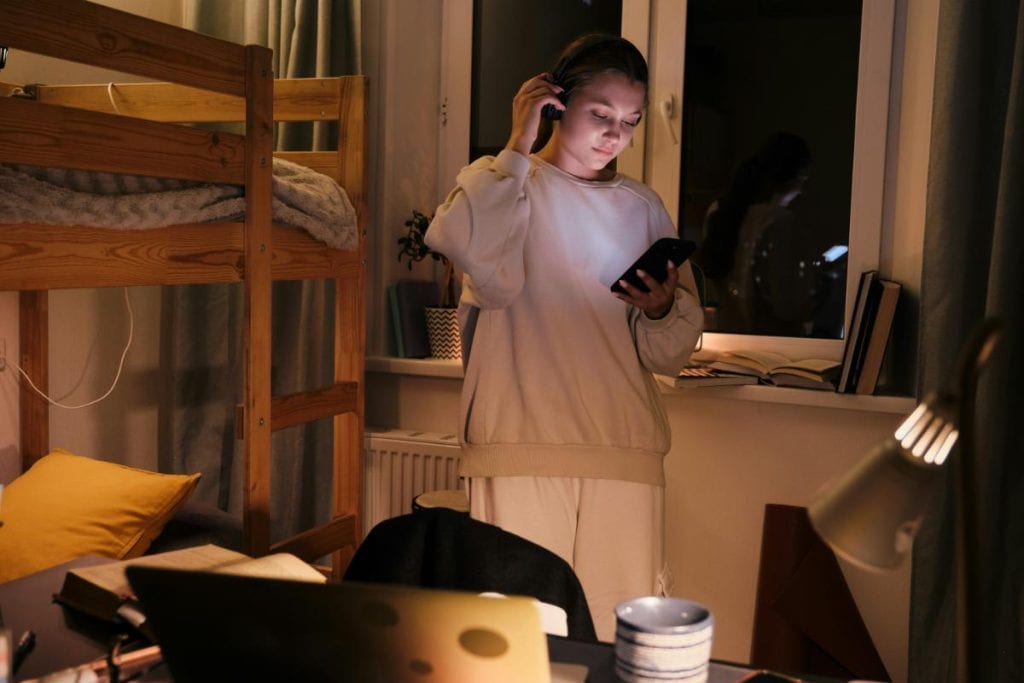 young woman looking at phone in dorm room