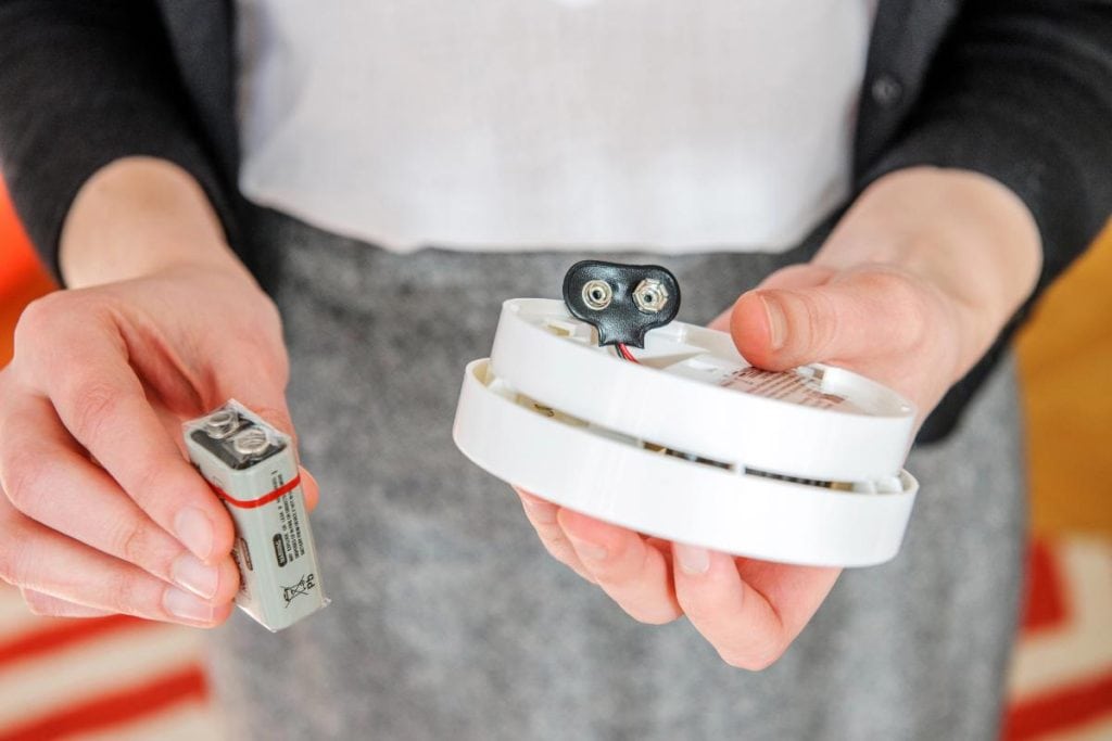 woman changing battery in smoke alarm