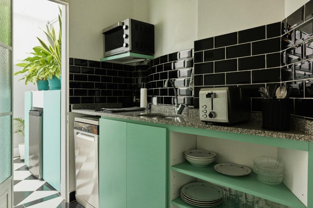 kitchen with black tile backsplash and colorful cabinets