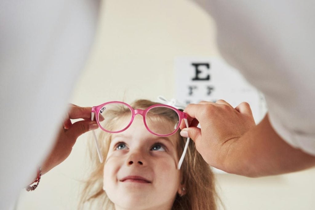 young girl trying on glasses with pink frames