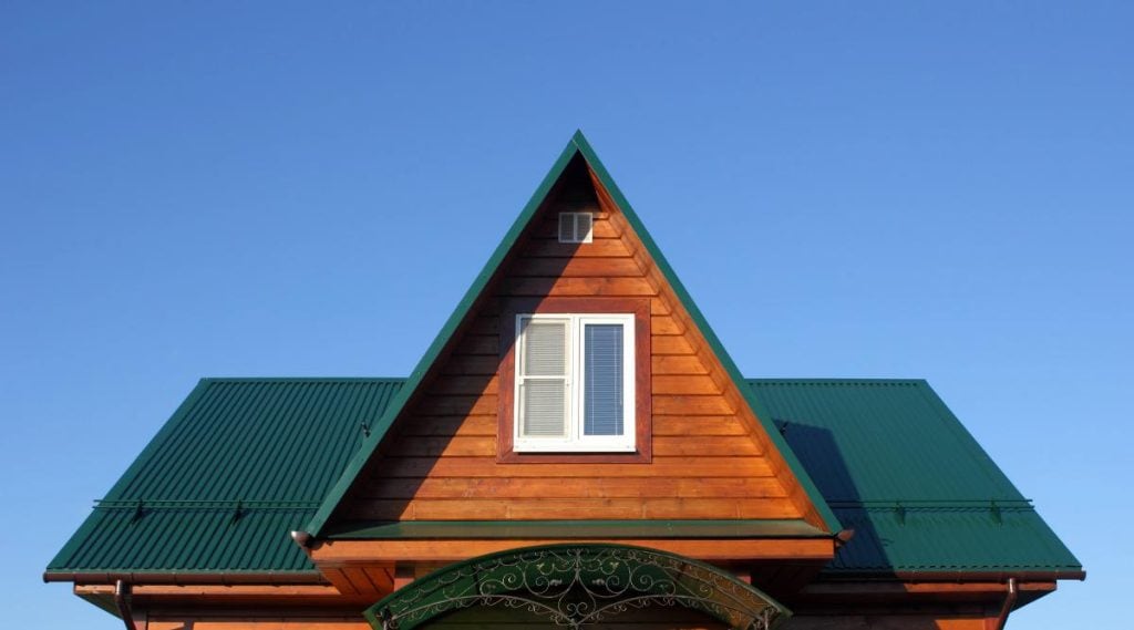 attic of house with wood siding and a green metal roof