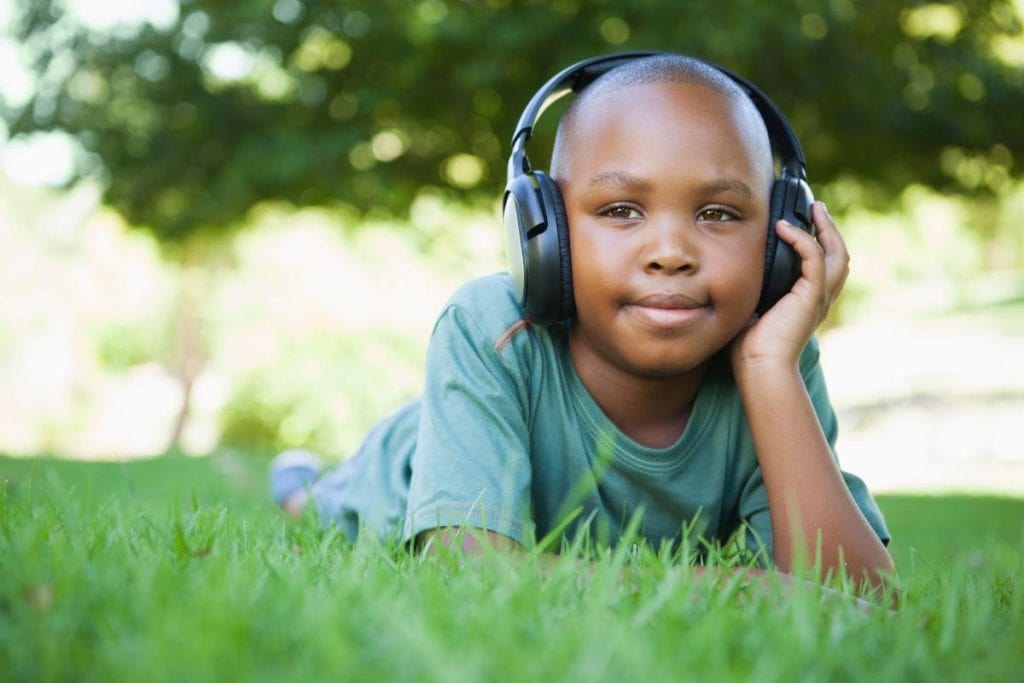 boy in grass with headphones on