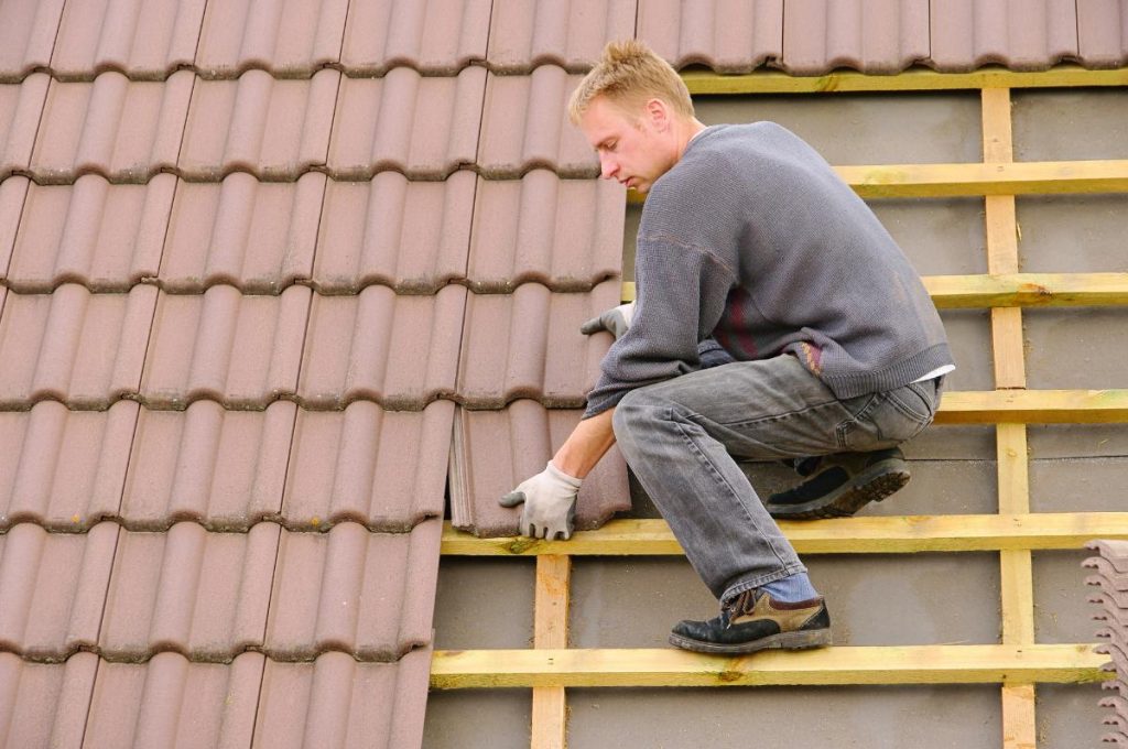 man installing tile on roof