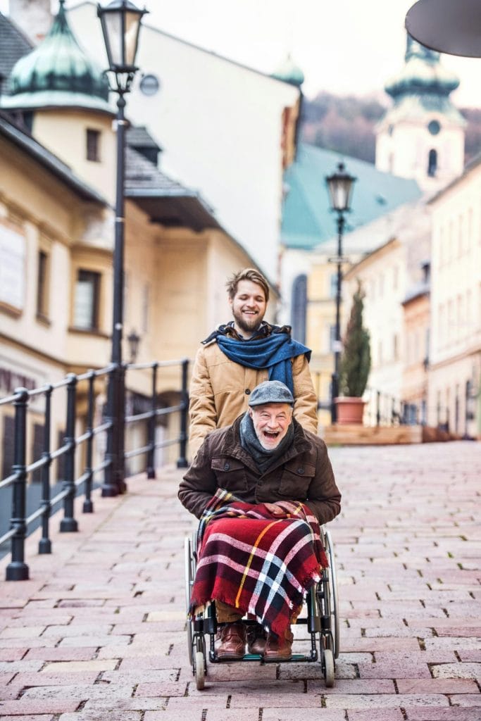 man pushing elderly father in wheelchair