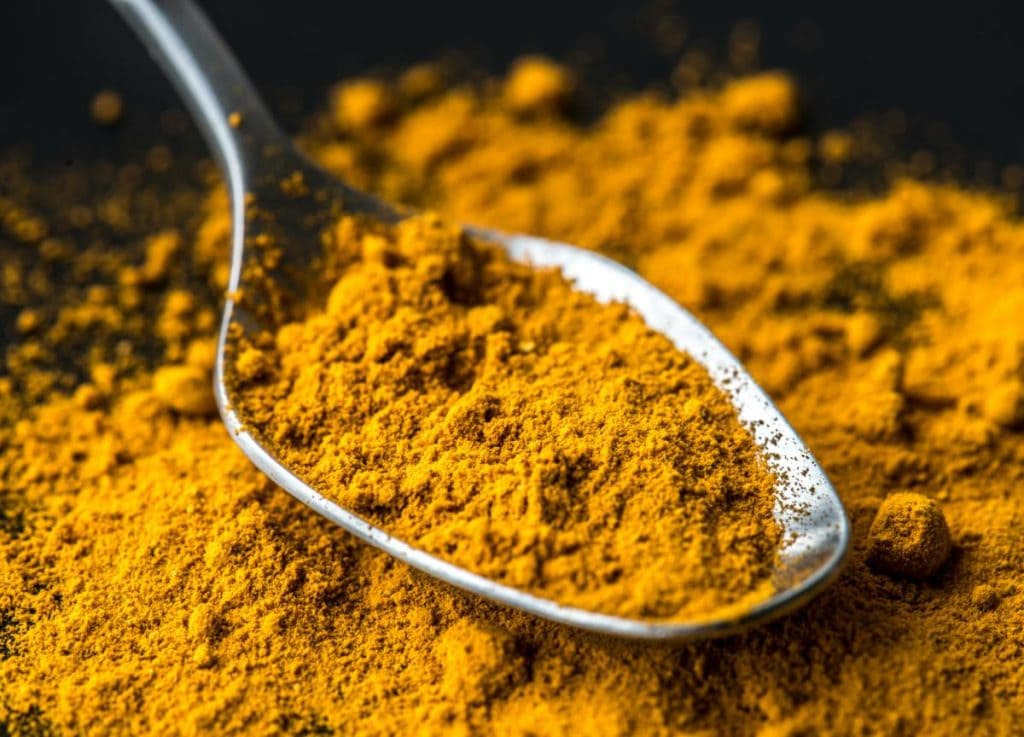 ground turmeric in a silver spoon