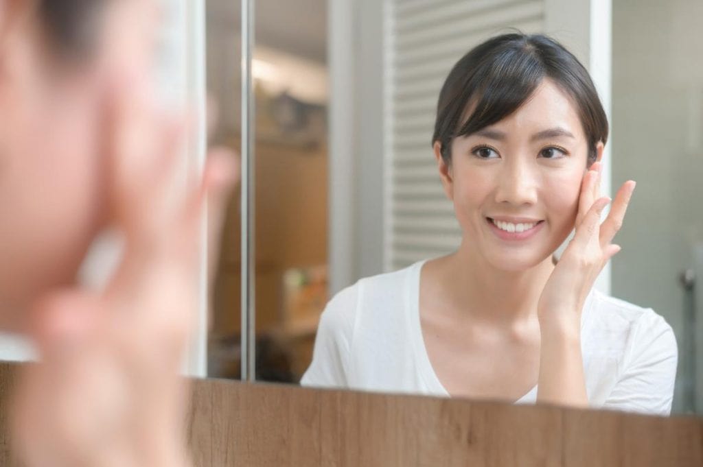 woman admiring youthful skin in mirror