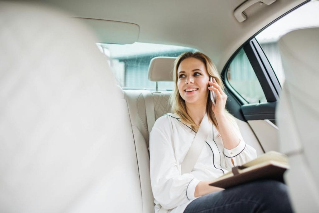 woman in backseat of car on her phone