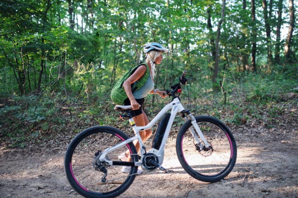 a woman riding a mountain ebike through the forest