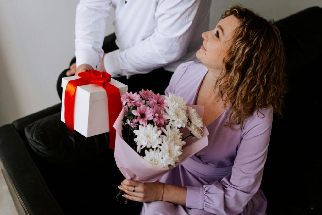 man giving wife flowers and a gift in a box