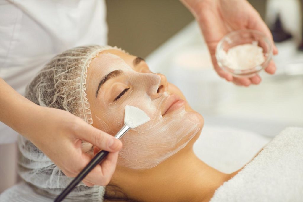 brushing a woman's face with moisturizing cream